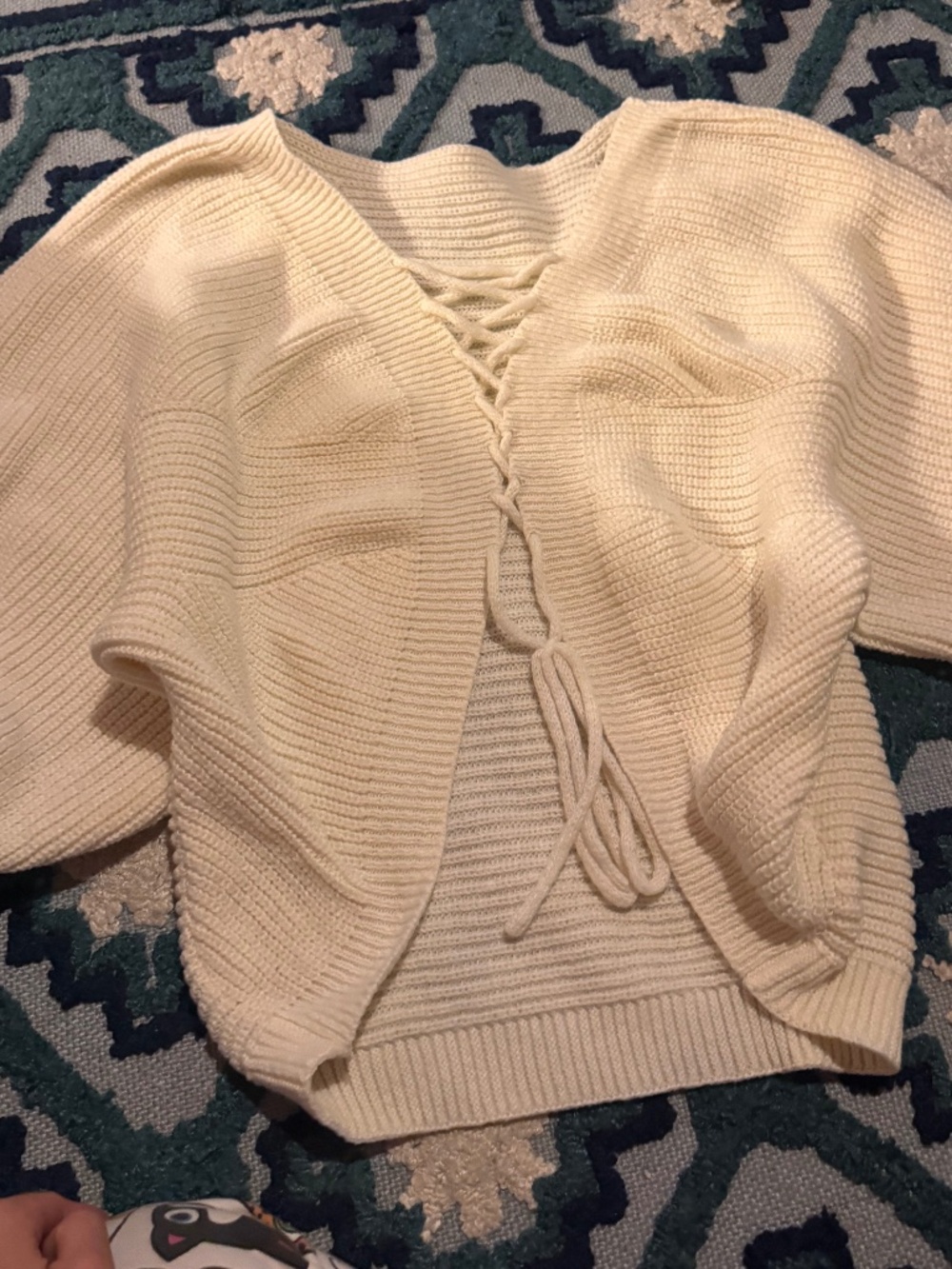 Soft cream knit sweater with a flattering lace-up V-neck. Lightweight ribbed tex